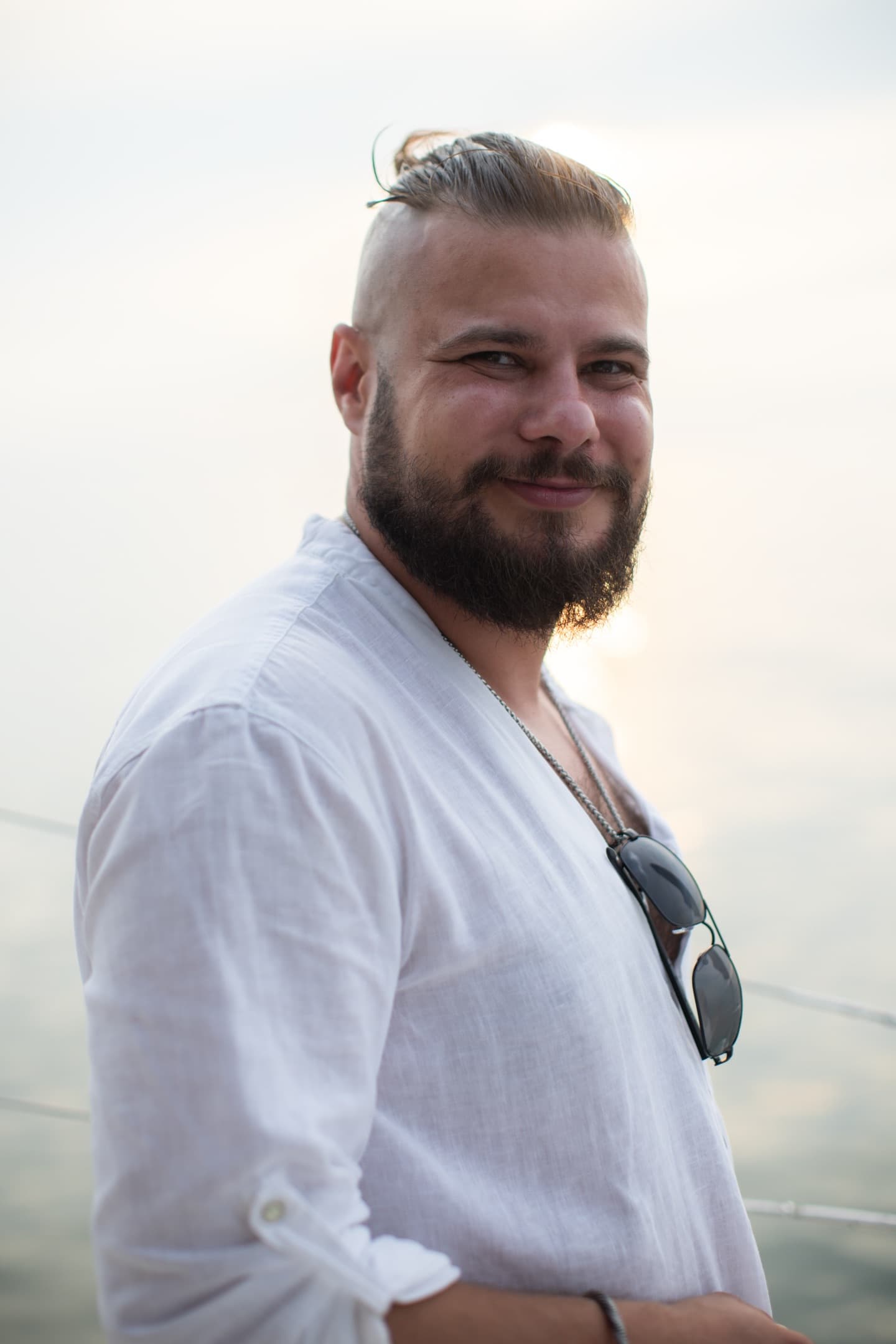Kobieta w kremowej ażurowej sukience siedzi z wyciągniętymi nogami na dachu jachtu, słoneczny, relaksacyjny nastrój.