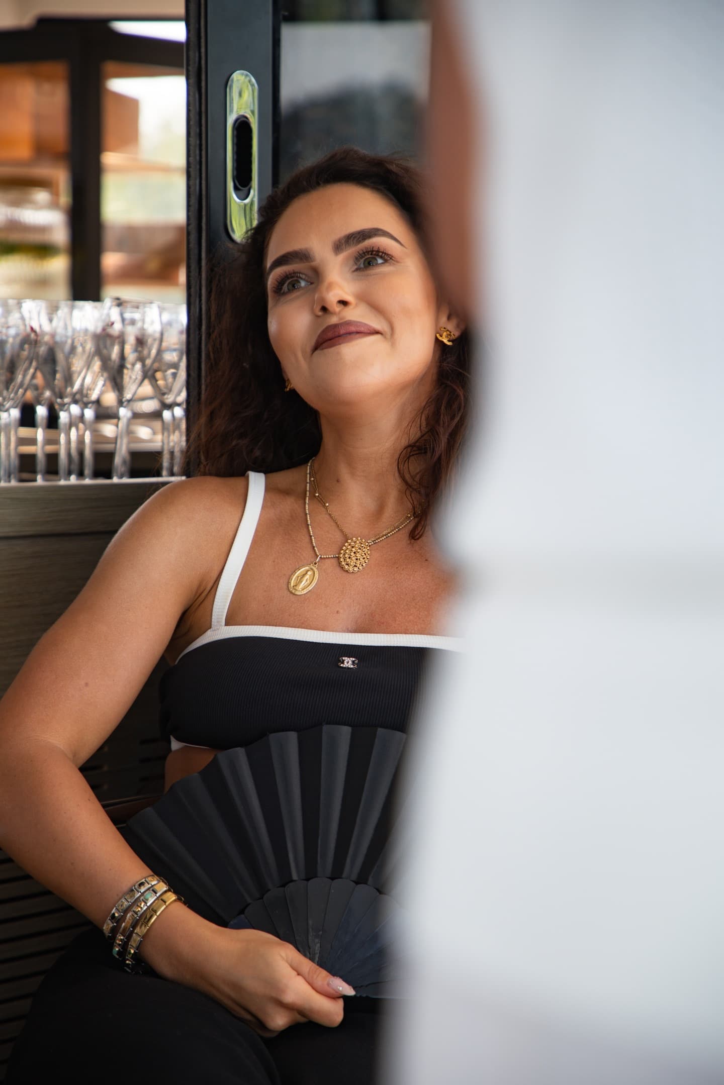 Trzy eleganckie osoby (łysy mężczyzna, blondynka w oliwkowej sukni, brodaty mężczyzna) trzymają kieliszki na tle czystego nieba, premium klimat.