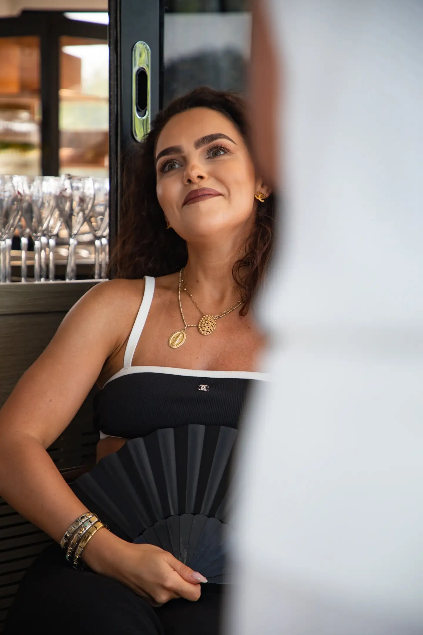 Trzy eleganckie osoby (łysy mężczyzna, blondynka w oliwkowej sukni, brodaty mężczyzna) trzymają kieliszki na tle czystego nieba, premium klimat.